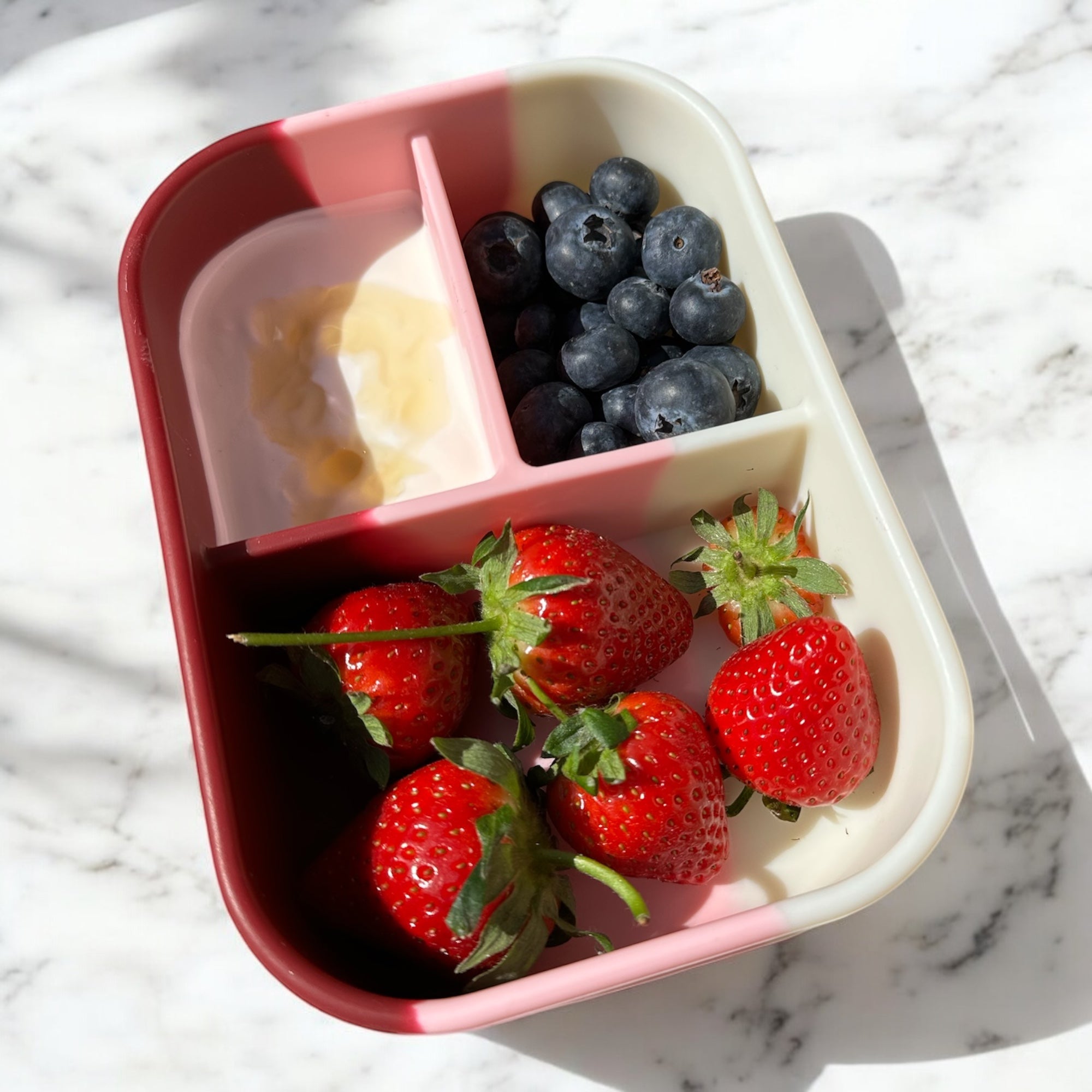 Berry Blush 3 compartment silicone bento box filled with strawberries, blueberries and yogurt, reusable kids lunch box for healthy snacks and school lunches