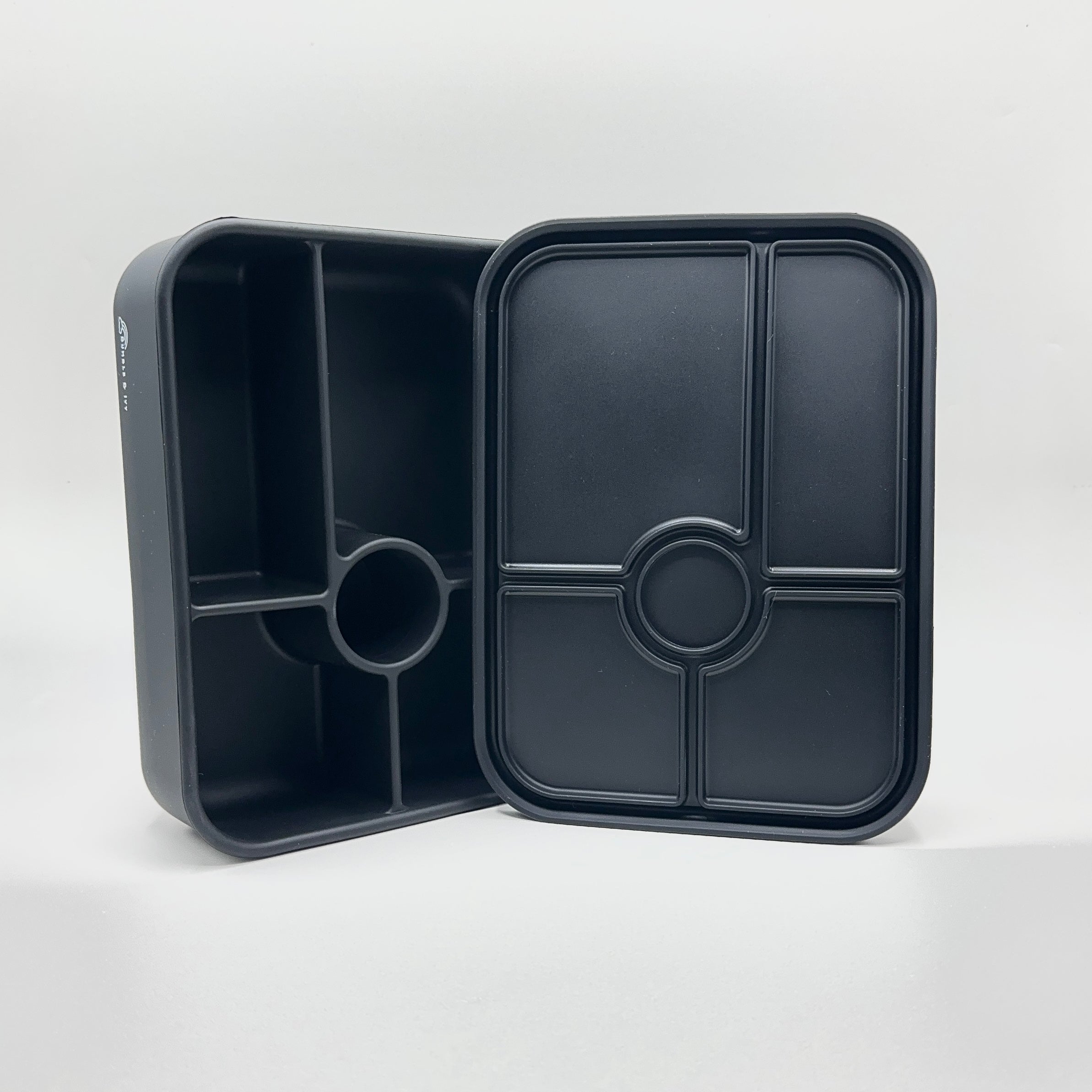 An open, upright view of the Bumble & Ivy midnight black silicone bento box and lid on a white background, displaying the 5 compartments and leakproof silicone seals