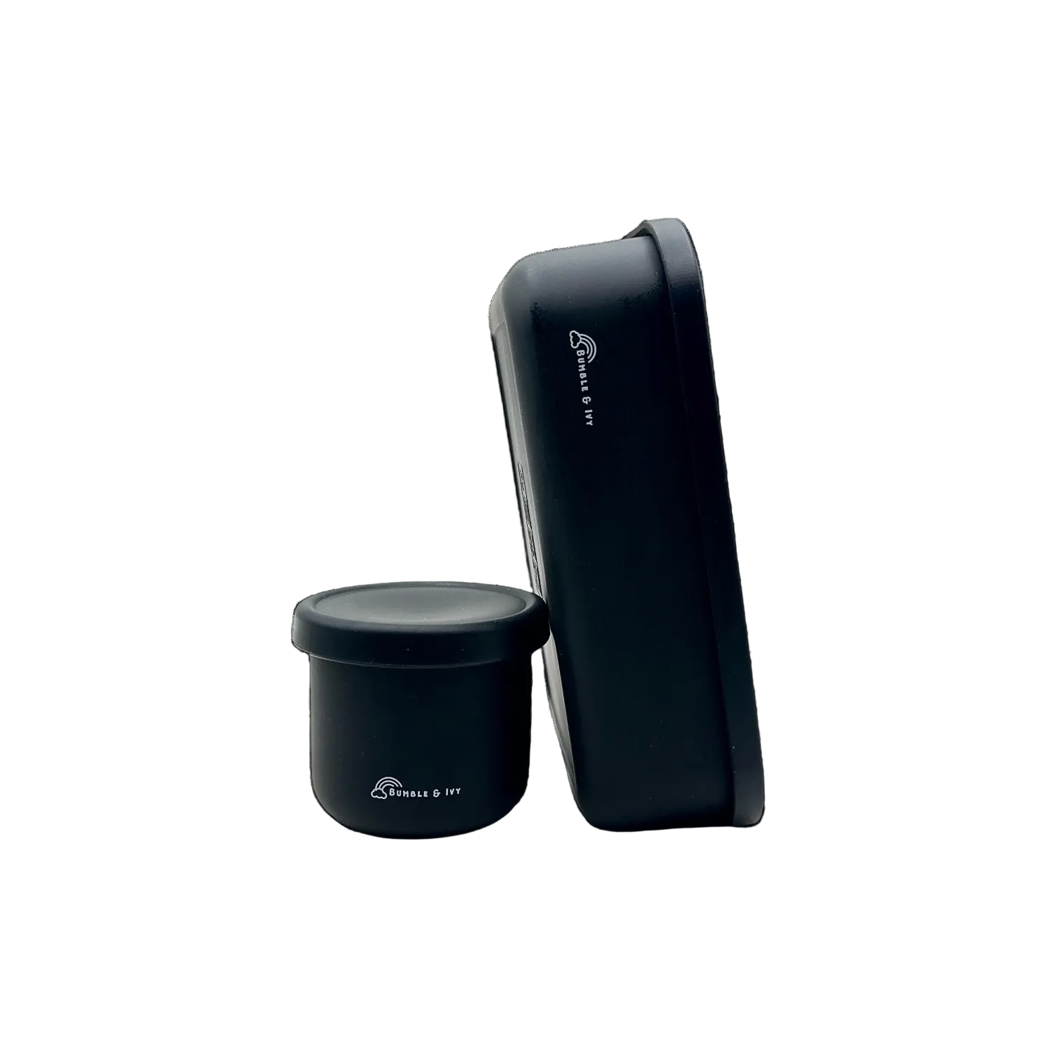 Side profile view of a midnight black silicone bento box and small snack pot by Bumble & Ivy, highlighting the deep, leakproof food compartments for kids' lunches.