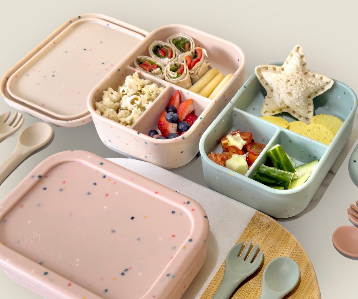 Bumble & Ivy Speckled Sage and Speckled Bubblegum silicone bento lunch boxes filled with healthy snacks and sandwiches. Reusable BPA-free lunch boxes for toddlers, nursery, school lunches and family outings.