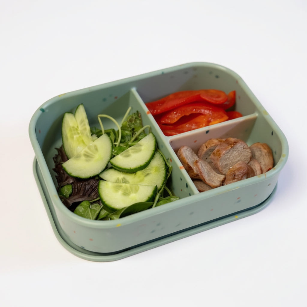 Bumble & Ivy Speckled Sage 3 compartment silicone bento lunch box filled with cucumber, salad, red pepper and chicken. Reusable BPA-free lunch box for toddlers, nursery, school lunches and healthy family meals.