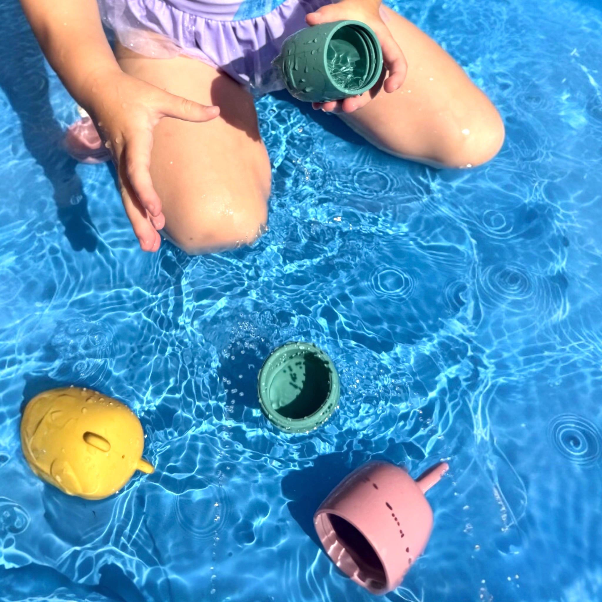 Child playing in water with Bumble & Ivy Woodland Bath Toys. Easy-clean mould-resistant silicone bath toys that open for cleaning, designed for sensory play, water play and toddler bath time fun.